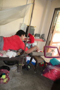 Man organizes the thread of his wool on a hardware that is set within reach. Profile view of man working in front lying to organize wool thread for craft-making. The hardware is place on a low table so he can work at chest height.